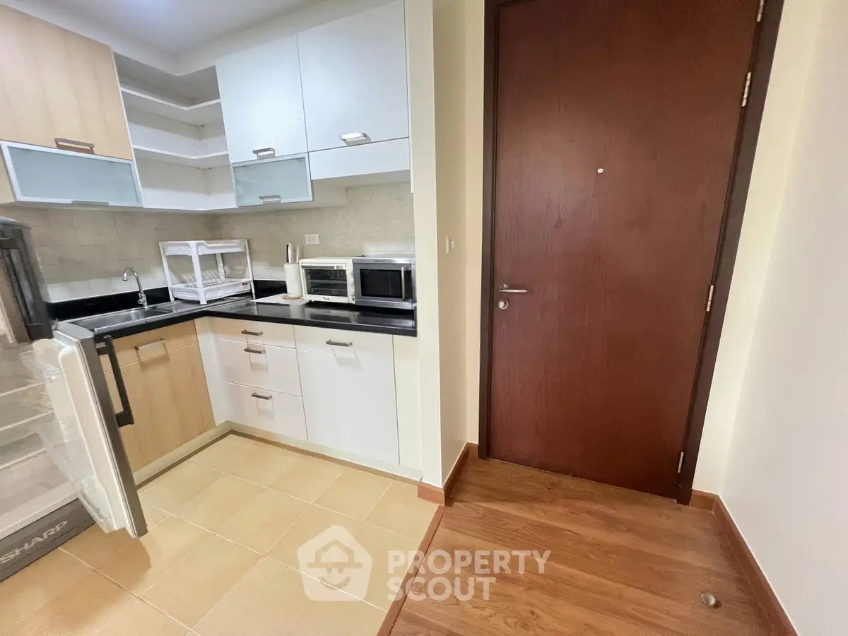 Modern kitchen with sleek cabinetry and appliances in a cozy apartment setting.
