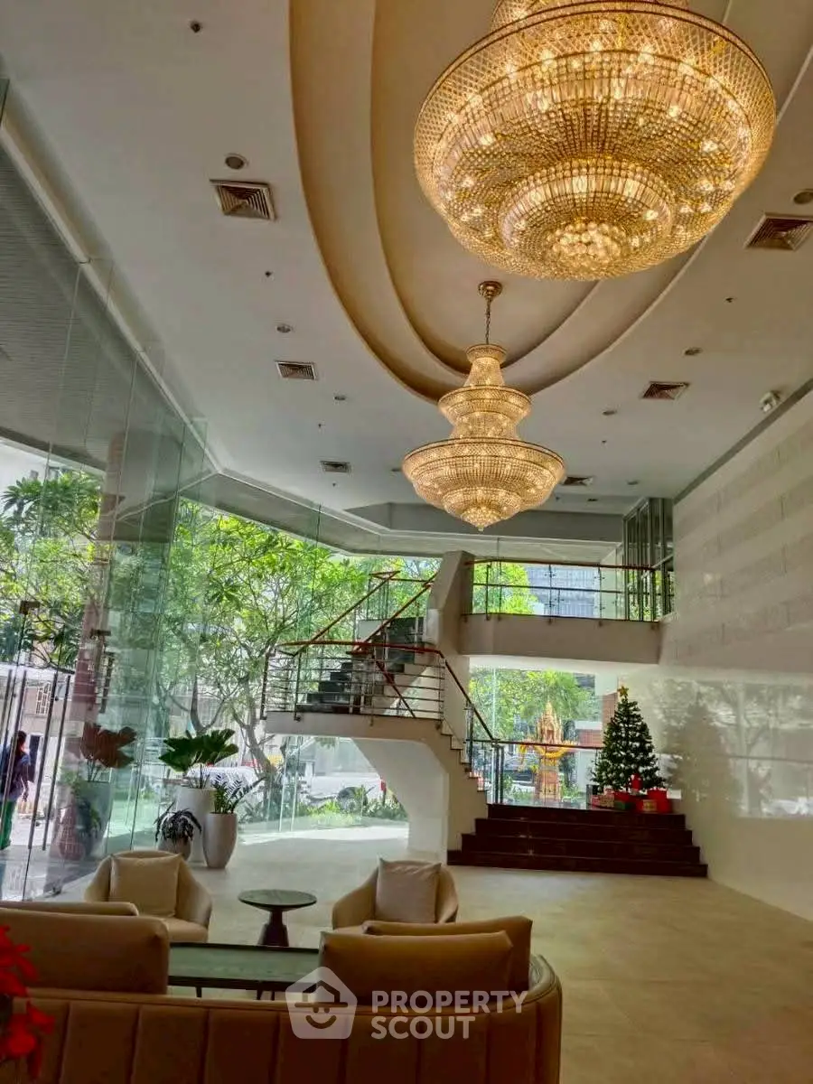 Luxurious lobby with grand chandeliers and elegant staircase in modern building.