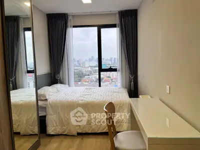 Modern bedroom with city view, featuring a cozy bed, desk, and large window.