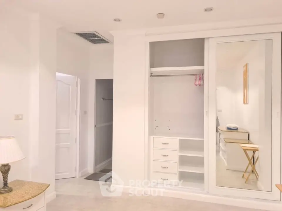 Spacious white bedroom with built-in closet and modern decor