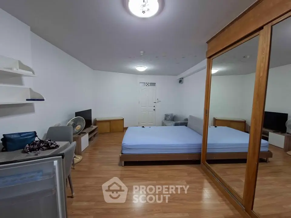 Spacious bedroom with mirrored wardrobe and wooden flooring