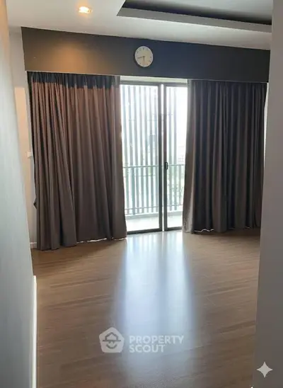 Spacious living room with large windows and elegant curtains, perfect for natural light.