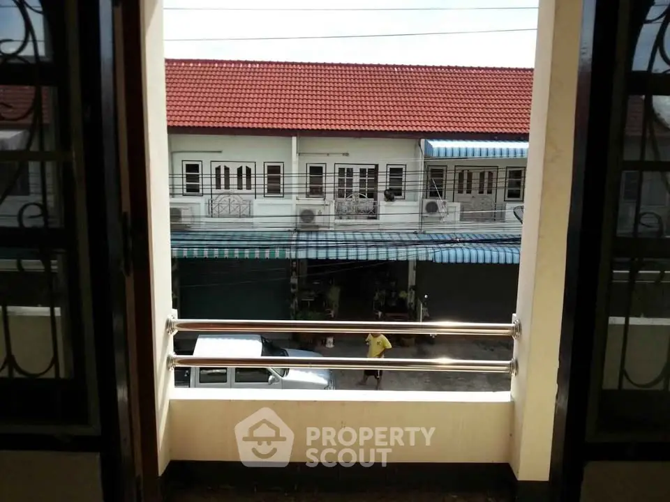 Charming balcony view overlooking residential street with red-roofed houses.