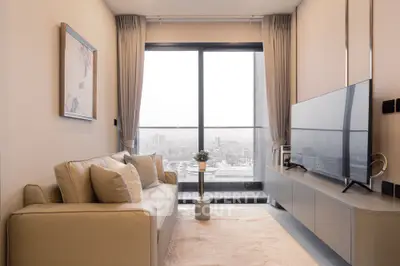 Modern living room with large window and city view, featuring a sleek sofa and flat-screen TV.
