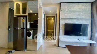 Modern apartment interior with sleek kitchen and living area featuring a wall-mounted TV and stylish decor.