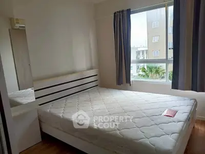 Cozy bedroom with large window and modern furnishings in a bright apartment.