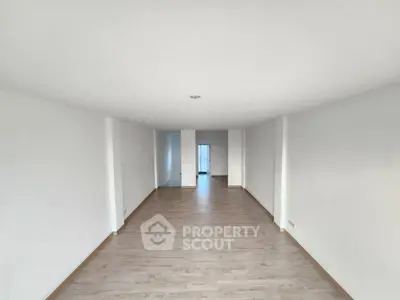 Spacious empty room with wooden flooring and white walls, ideal for customization.
