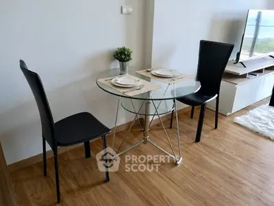 Modern living room with glass dining table and sleek black chairs, featuring a stylish TV setup.