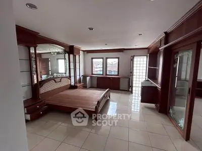 Spacious bedroom with elegant wooden furniture and large windows for natural light.