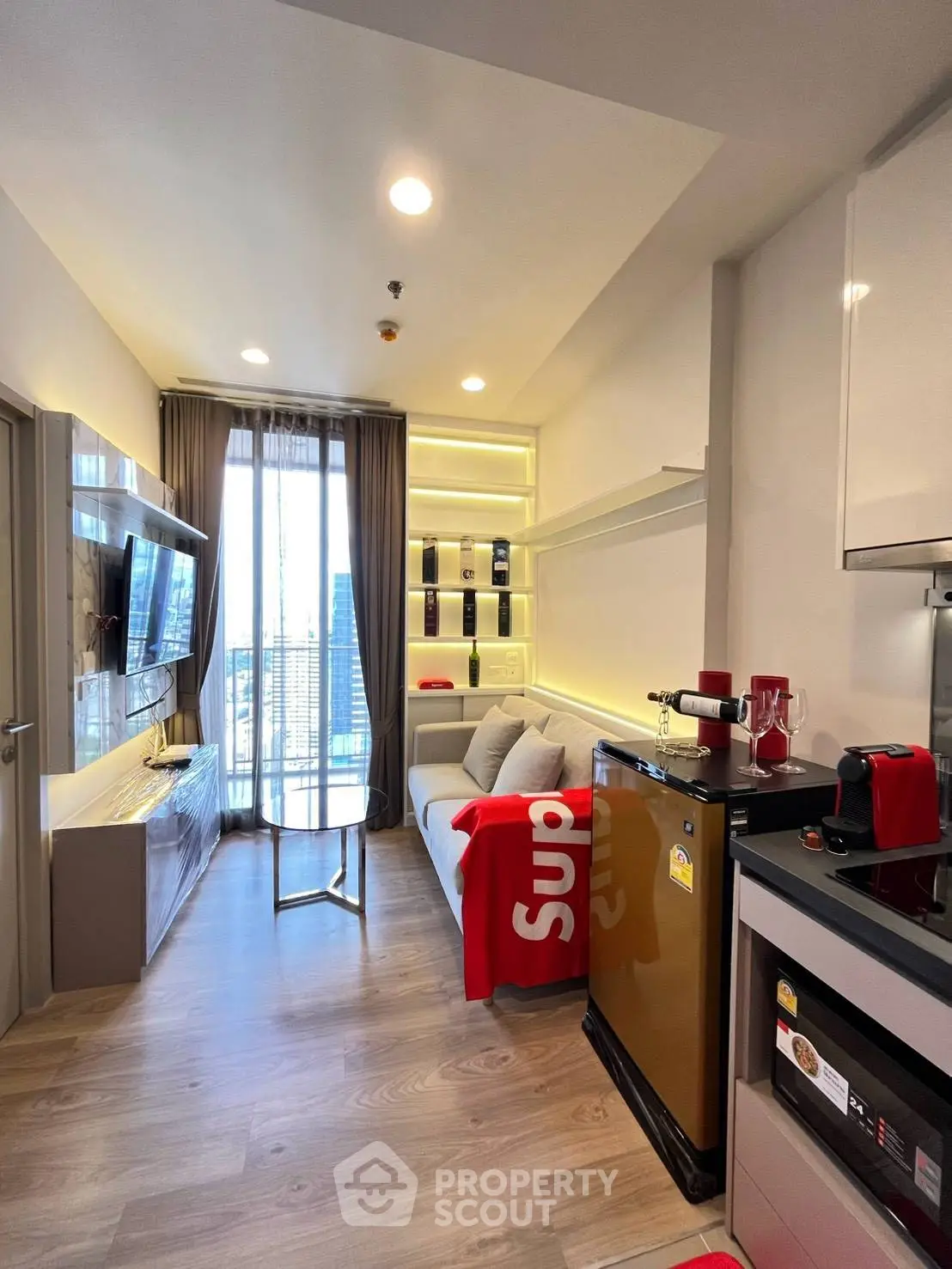 Modern living room with sleek design, featuring a cozy sofa, stylish shelving, and a compact kitchen area.