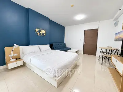 Modern bedroom with blue accent wall, cozy bed, and stylish furniture in a contemporary apartment.