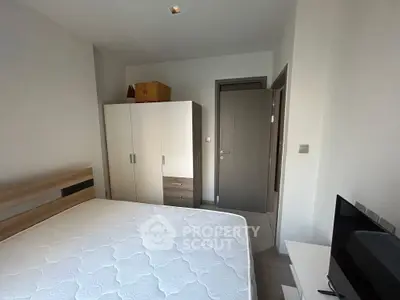 Modern bedroom with minimalist design featuring a comfortable bed, wardrobe, and flat-screen TV.