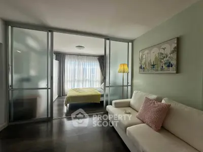 Modern studio apartment with sliding glass doors separating bedroom and living area, featuring stylish decor.