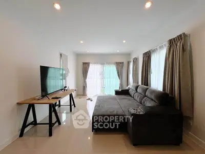 Spacious living room with modern sofa and large TV, perfect for relaxation and entertainment.