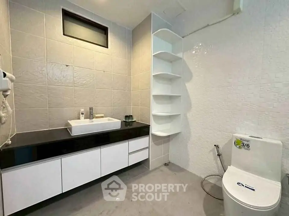 Modern bathroom with sleek vanity and wall-mounted shelves in a contemporary home.