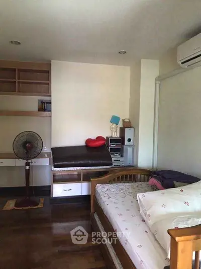 Cozy bedroom with wooden furniture and air conditioning, perfect for relaxation.