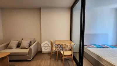 Modern studio apartment with cozy living area and bedroom separated by glass partition.