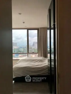 Cozy bedroom with large window offering stunning city views, perfect for urban living.