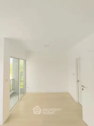 Spacious empty room with sliding glass doors leading to a balcony, perfect for customization.