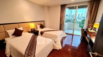 Luxurious twin bedroom with city view and balcony access, featuring elegant decor and hardwood floors.