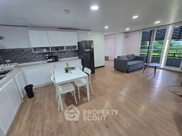Spacious open-layout kitchen and living area with modern appliances and balcony view.