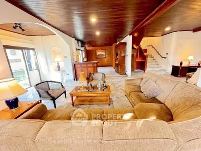 Spacious living room with elegant wooden ceiling and cozy seating area in luxury home.