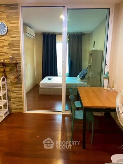 Cozy bedroom with wooden flooring and glass partition, featuring a study table and modern decor.