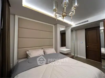 Luxurious bedroom with elegant chandelier and mirrored wardrobe in modern apartment.