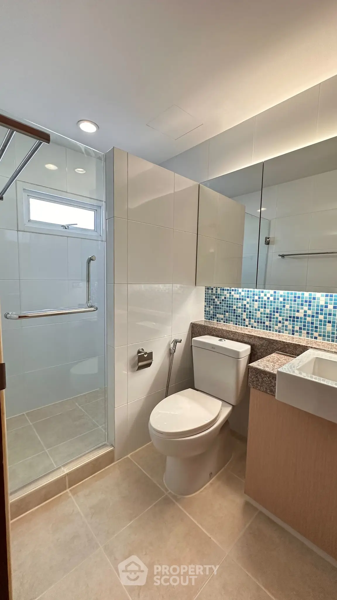Modern bathroom with sleek design, featuring a glass shower and stylish mosaic backsplash.