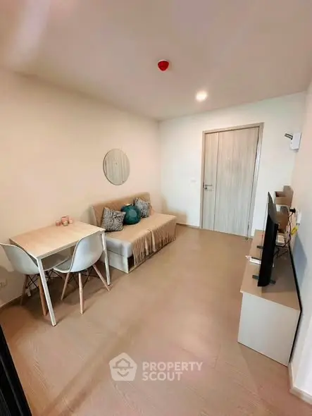 Cozy living room with modern decor, featuring a sofa, dining table, and wall-mounted TV for a comfortable lifestyle.