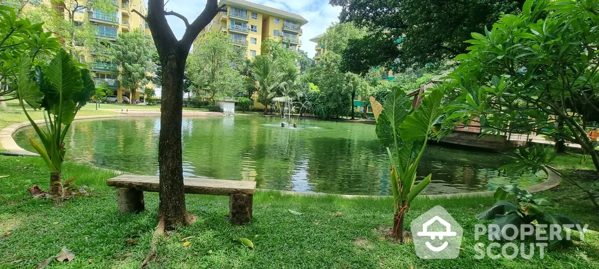 Serene garden oasis with a tranquil pond, lush greenery, and a charming bench, nestled within a residential community, offering a peaceful retreat.