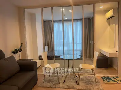 Modern studio apartment with glass partition, cozy seating, and stylish decor.