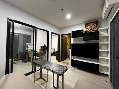 Modern living room with sleek furniture and sliding glass doors leading to a cozy bedroom.