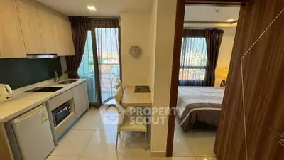 Modern apartment interior with kitchen and bedroom, featuring sleek design and natural light.