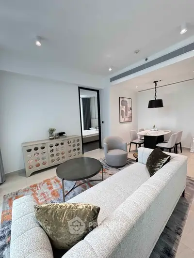 Modern living room with elegant decor and open dining area, featuring plush seating and stylish accents.