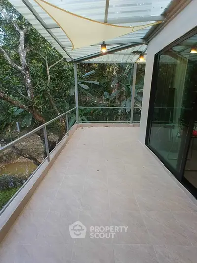 Spacious balcony with glass railing and forest view, perfect for relaxation and outdoor enjoyment.