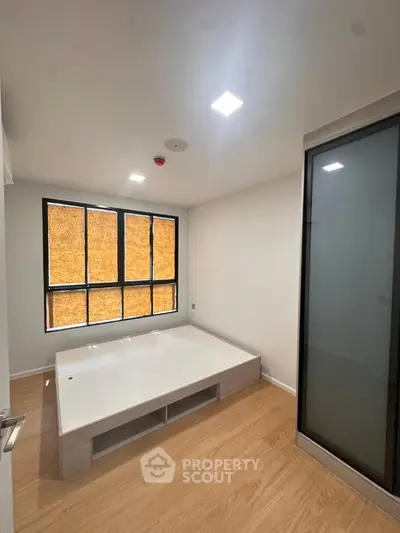 Modern minimalist bedroom with wooden flooring and large window