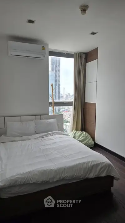 Modern bedroom with city view, featuring a cozy bed and air conditioning, perfect for urban living.