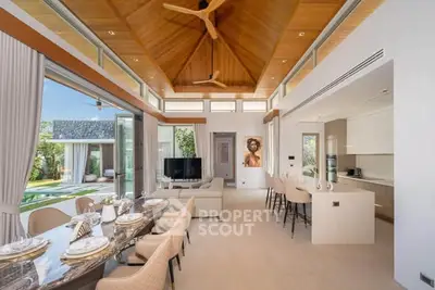 Luxurious open-plan living room with high ceilings and elegant dining area, overlooking a lush garden.