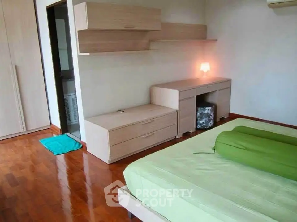 Spacious bedroom with modern wooden furniture and polished hardwood floors.