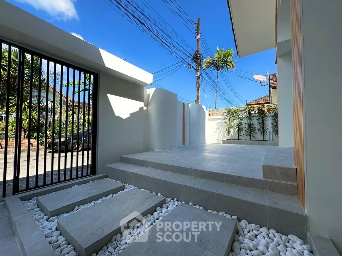 Modern minimalist entrance with sleek stone steps and lush greenery, perfect for contemporary living.