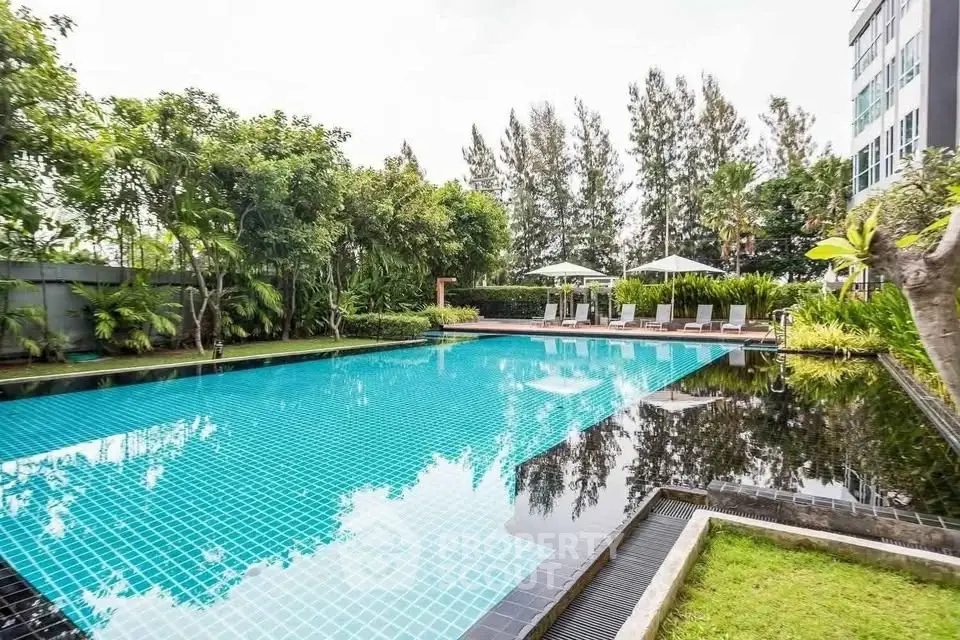 Luxurious outdoor pool surrounded by lush greenery in a modern residential complex.