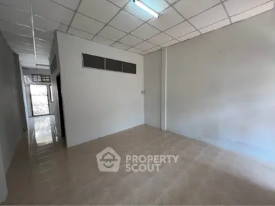 Spacious empty room with tiled floor and fluorescent lighting, ideal for customization.