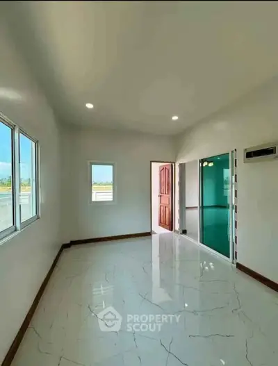 Bright and spacious room with glossy tiled flooring and large windows, perfect for modern living.