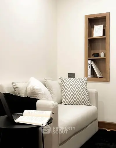 Cozy modern living room with stylish sofa and built-in wall shelf, perfect for relaxation and reading.