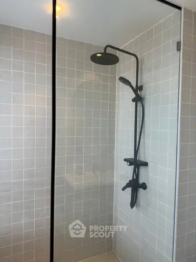 Modern bathroom with sleek black shower fixtures and neutral tile design.