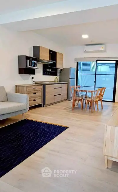 Modern open-plan living room with kitchen and dining area, featuring sleek furniture and natural light.