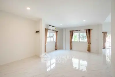 Spacious and bright living room with large windows and elegant marble flooring.