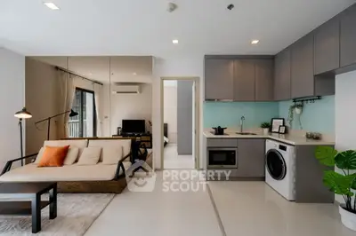Modern open-plan living room with kitchen, featuring sleek appliances and stylish decor.