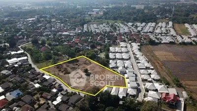 Aerial view of residential development site with outlined plot in suburban area.